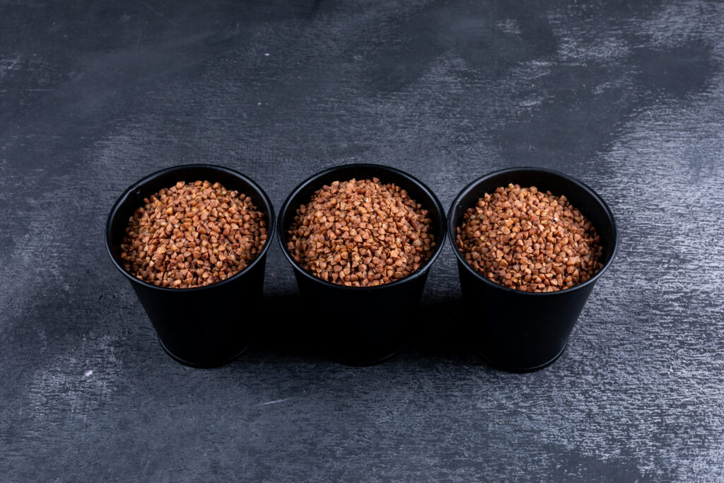 buckwheats in buckets on a dark gray background. high angle view.